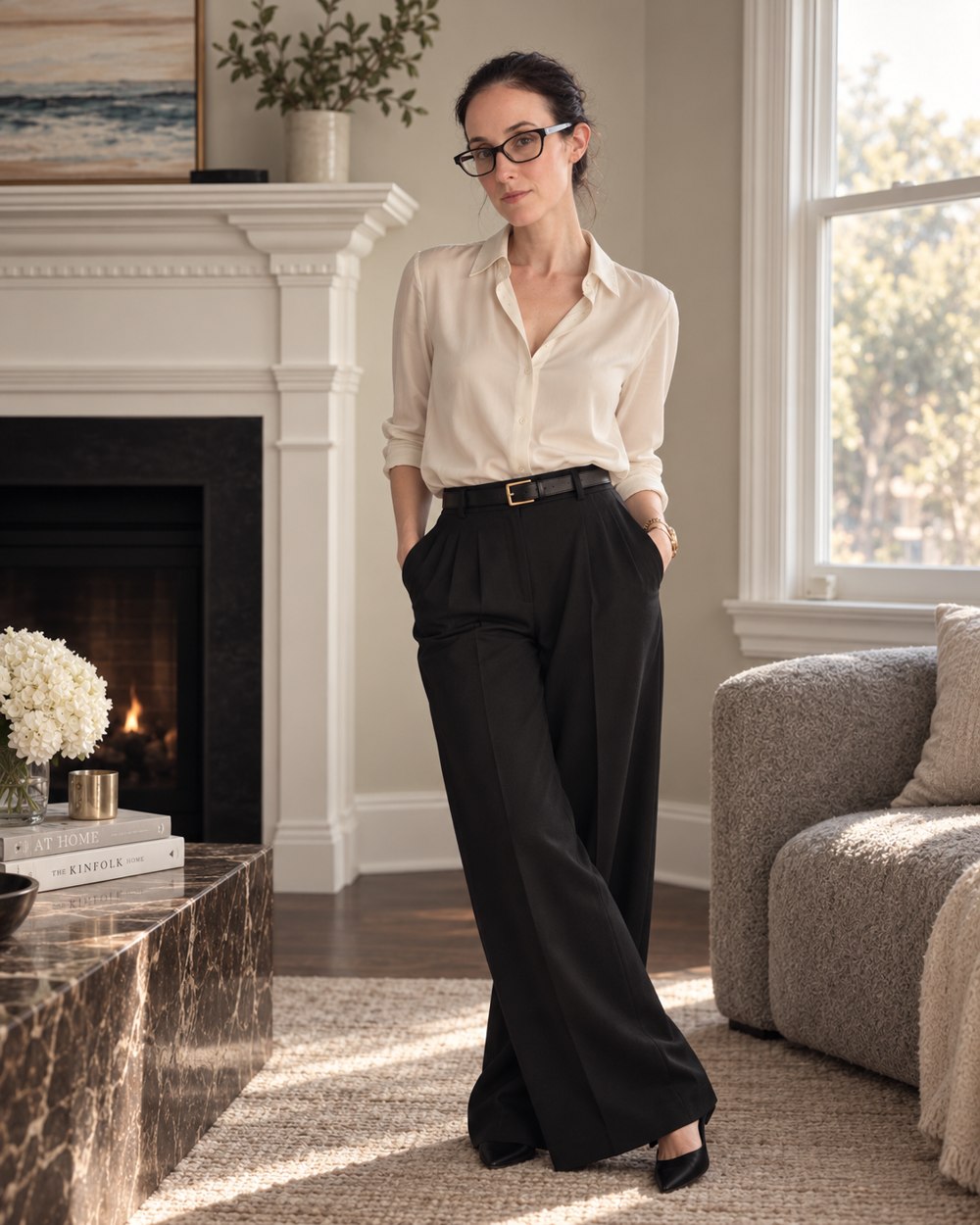 Kristin wearing a white shirt and black trousers by the living-room window